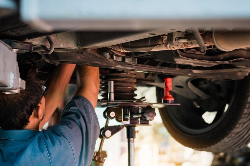 Mechanic repairing a car, Mechanic inspects car suspension system and chassis with a torch-lite under the car. Mechanic repairing a car, Mechanic inspects car suspension system and chassis with a torch-lite under the car.