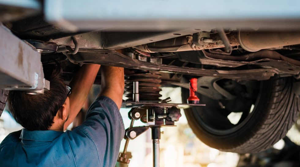 Mechanic repairing a car, Mechanic inspects car suspension system and chassis with a torch-lite under the car. Mechanic repairing a car, Mechanic inspects car suspension system and chassis with a torch-lite under the car.